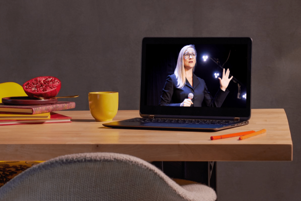 Laptop on desk showing Barbara, founder of virtualspacehero, giving a speech