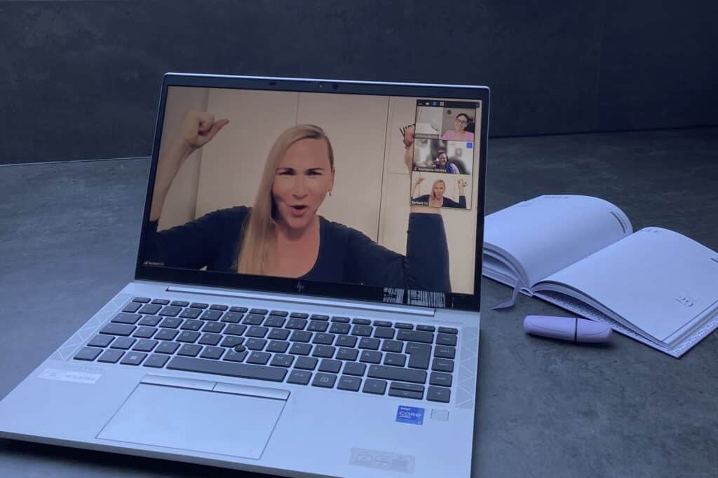 Laptop on desk showing Barbara, the founder of #VirtualSpaceHero, cheering into the camera.